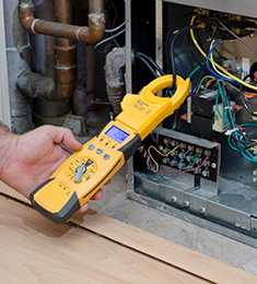 Hand holding electrical meter reader connected to wires